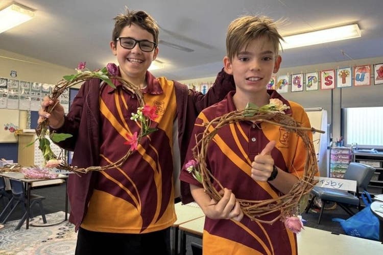 2 students holding grapevine wreaths they created